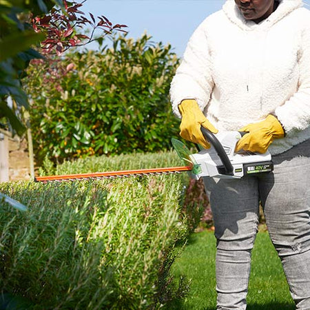 Woman using cordless hedge trimmer